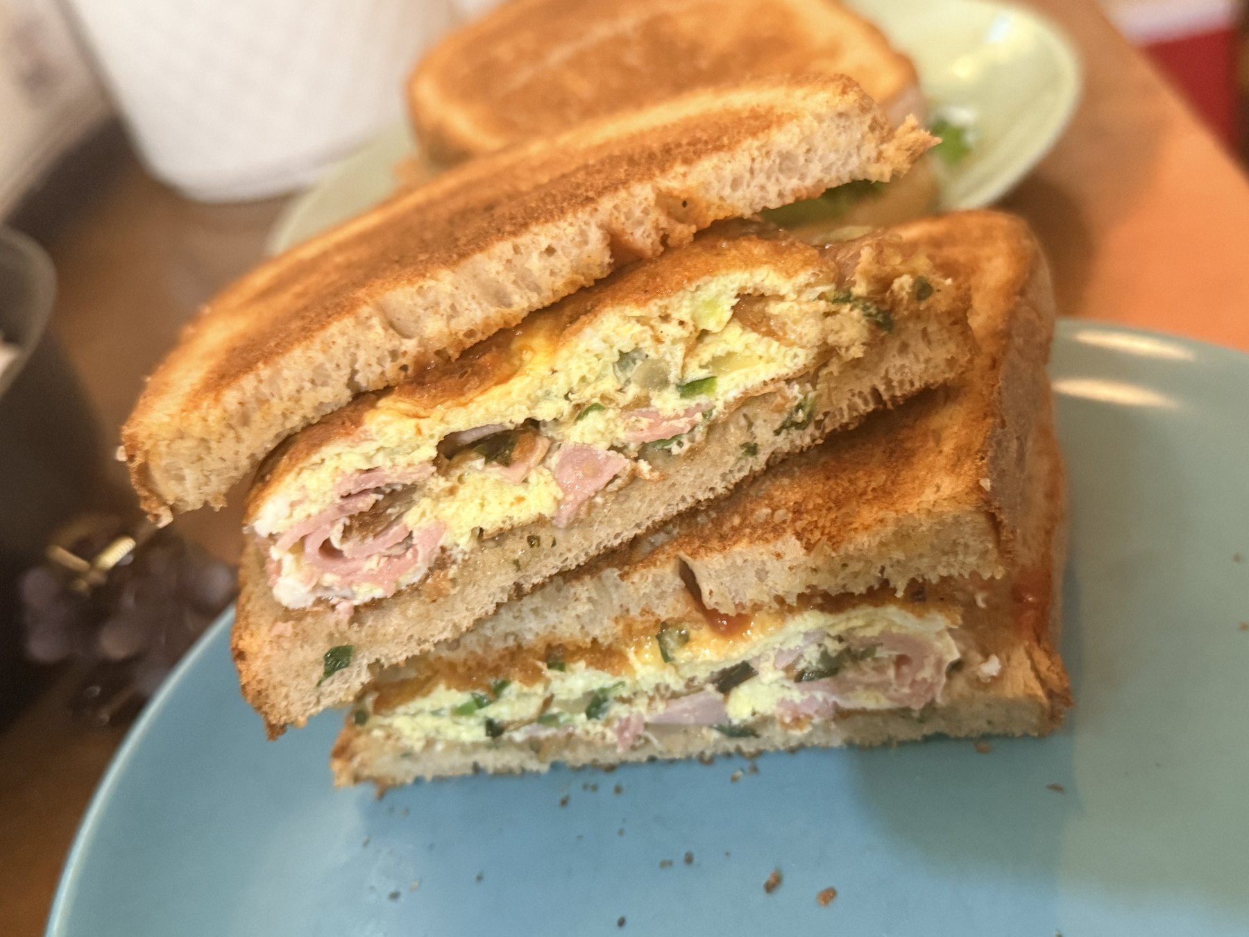 Western omelette sandwich stacked on a blue plate